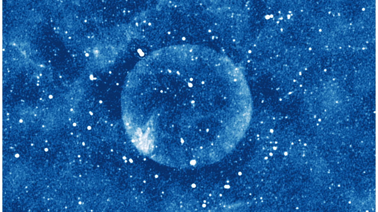 Imagem astronômica azulada, em baixa definição, mostra estrutura cósmica esférica.