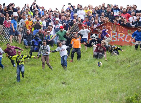 Fotografia dos participantes perseguindo o queijo na Cheese Rolling.