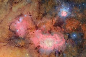 Fototografia das nuvens de gás e poeira que compõem a nebulosa Trífida (canto superior direito) e a nebulosa Lagoa, que estão a milhares de anos-luz de distância da Terra, podem ser vistas.