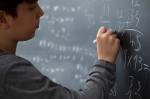 Fotografia de uma menino escrevendo equações de matemática na lousa.