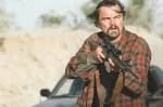 Fotografia do filme Uma Batalha Após a Outra. imagem do personagem do Leonardo DiCaprio segurando uma arma, olhando pra frente.