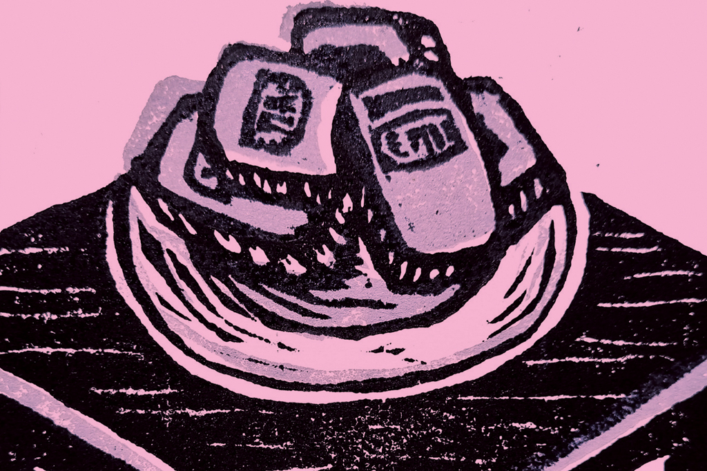 Imagem de uma xilogravura, em fundo rosa. V&ecirc;-se um prato em cima de uma mesa.