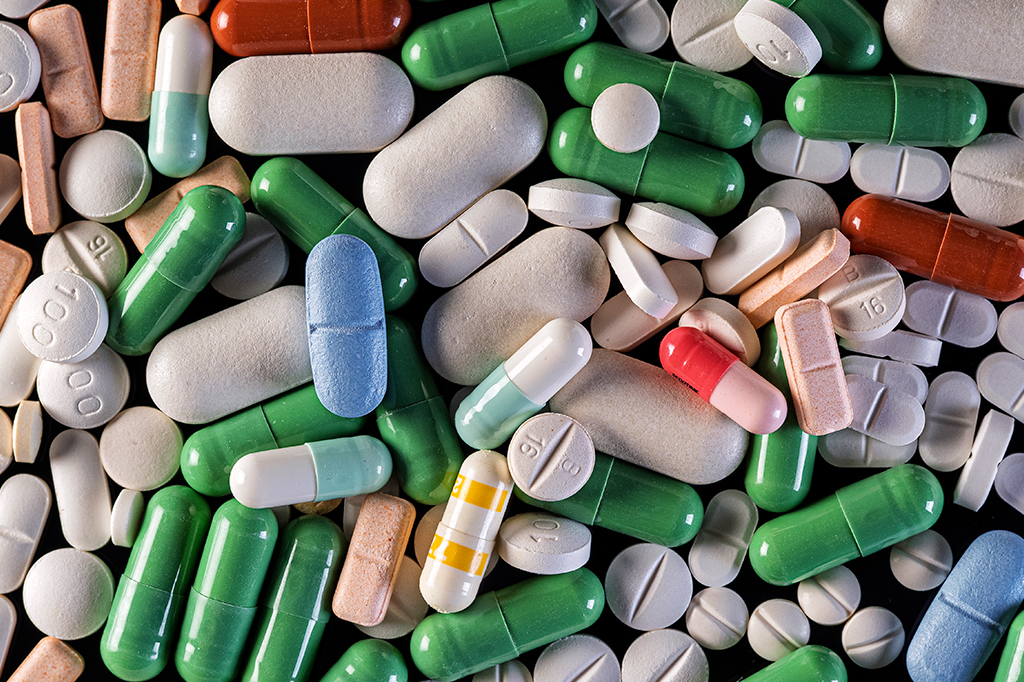 Fotografia de diferentes tipos de medicamentos em forma de comprimido e cápsula.