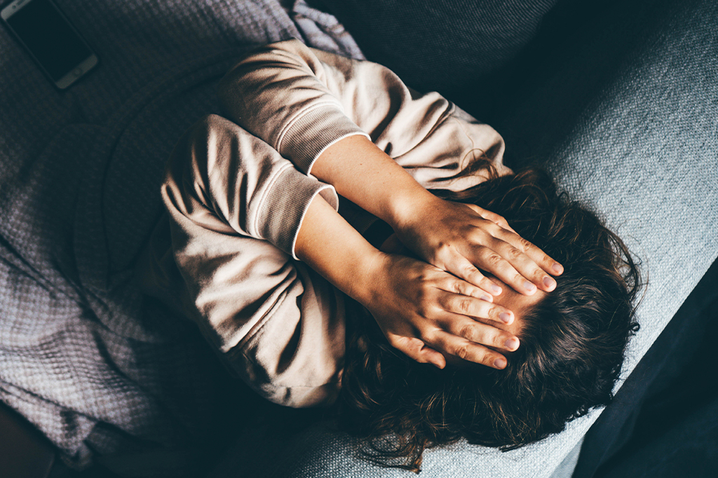 Fotografia de uma mulher com as mãos no rostos triste.