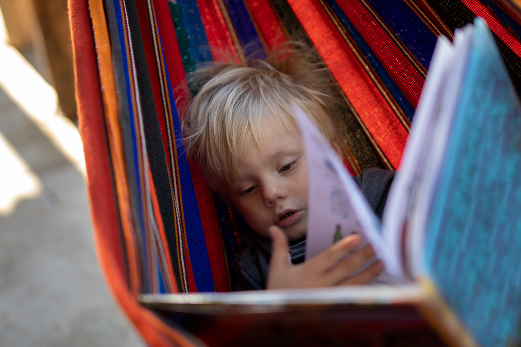 Fotografia de uma criança lendo enquanto estava deitado em uma rede.