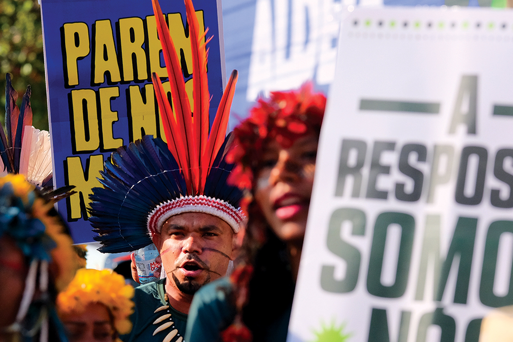 Imagem de pessoas reunidas carregando cartazes de protesto.