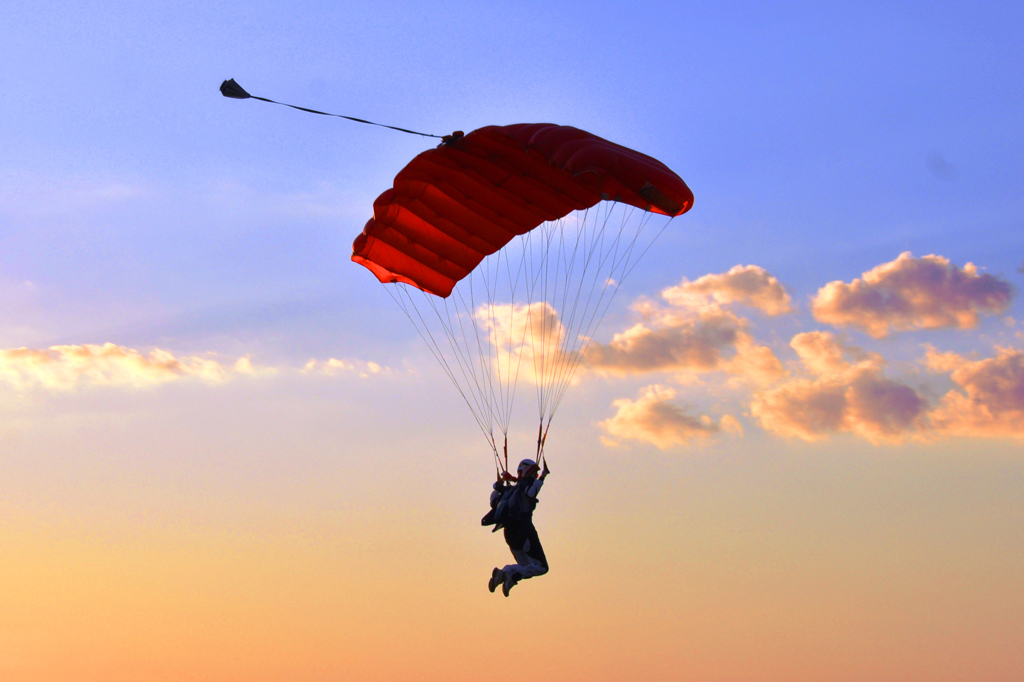 Imagem de um paraquedista deslizando entre nuvens.