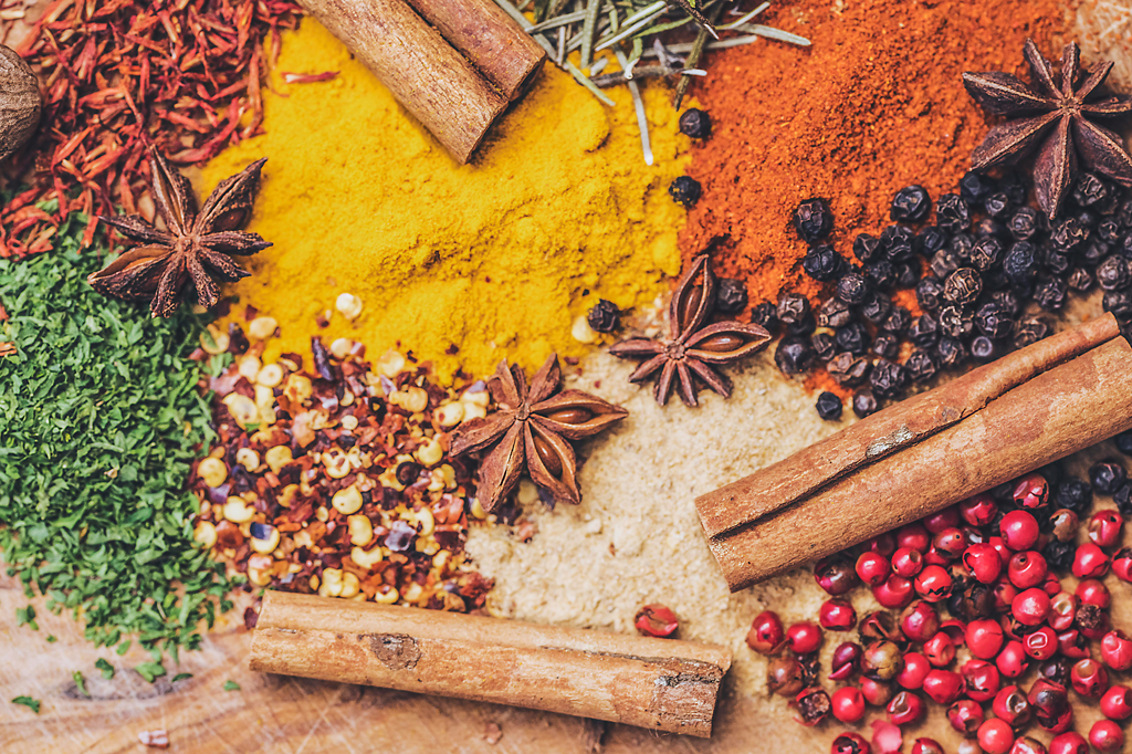 Imagem, vista de cima, de diversos tipos de temperos espalhados sobre um balcão.