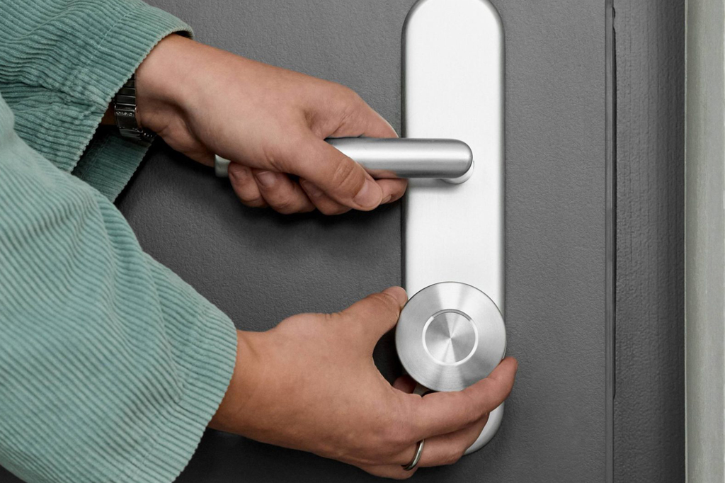 Imagem, focada nas m&atilde;os, de uma pessoa abrindo uma porta.