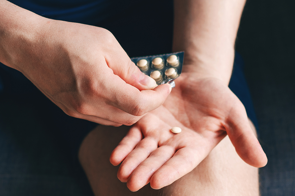 Imagem aproximada de uma pessoa segurando uma embalagem de remédios.