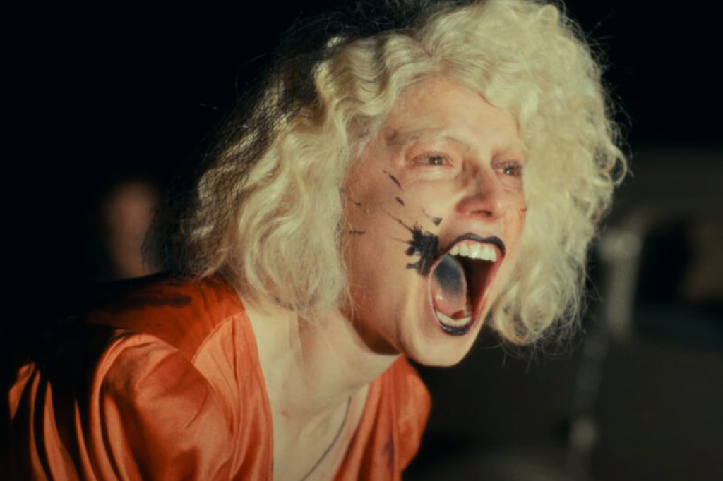 Imagem do filme A noiva! V&ecirc;-se uma mulher loira berrando com a boca manchada de batom preto.