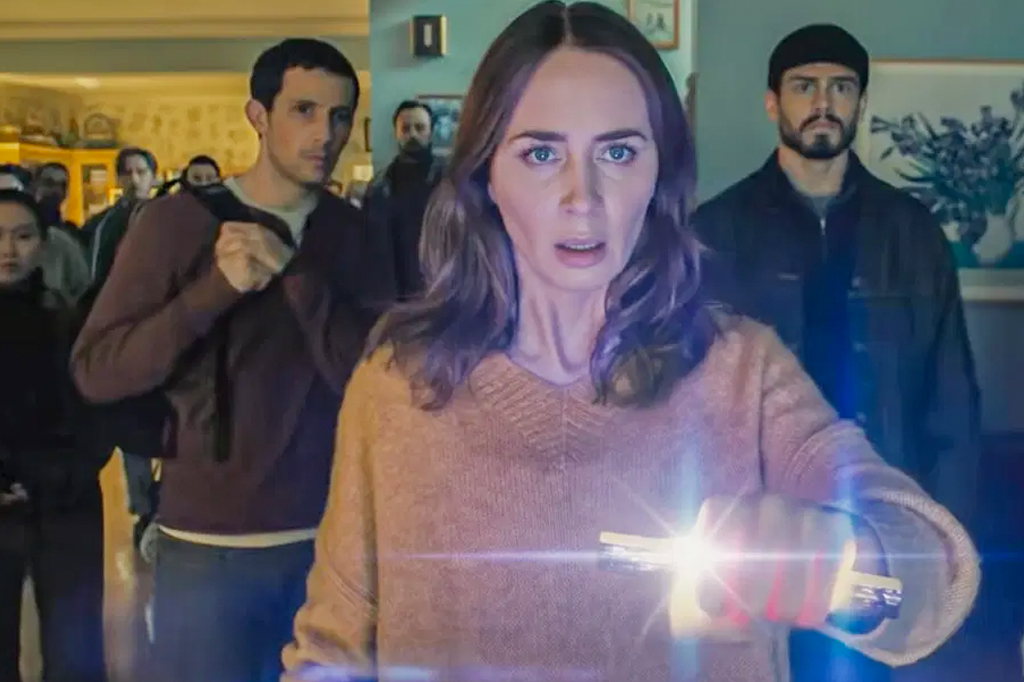 Imagem do filme Dia D. V&circ;-se um grupo de pessoa olhando para frente com rostos assustados. A frente, uma mulher segura um objeto cil&iacute;ndrico.