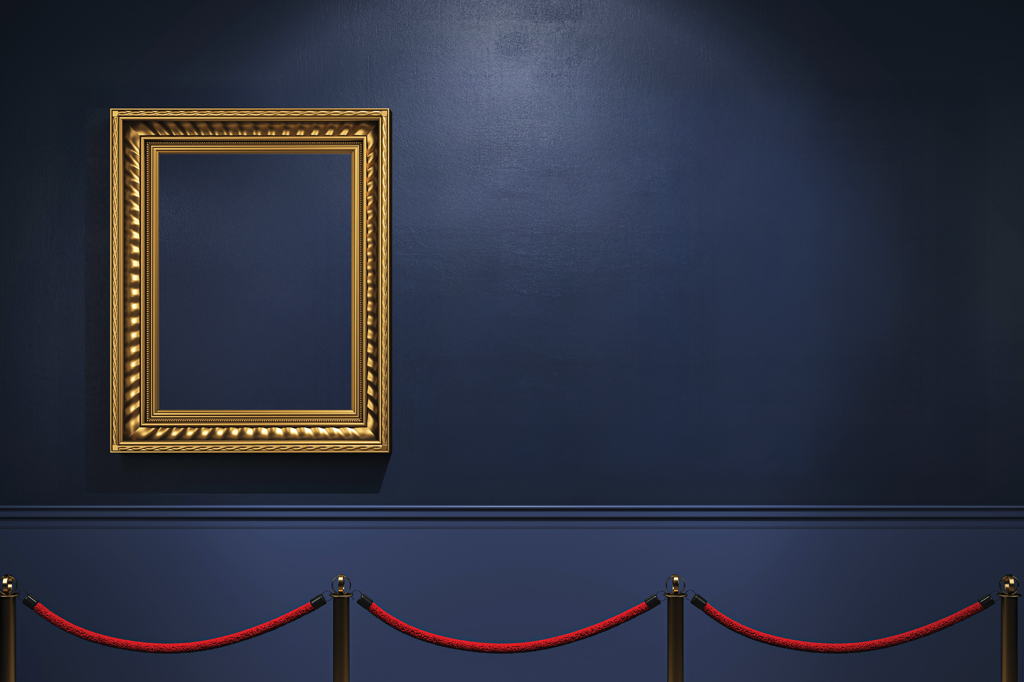 Imagem de uma sala de museu pintada de azul marinho, expondo um quadro de moldura dourada sem tela. A frente, vê-se cordas vermelhas de segurança.