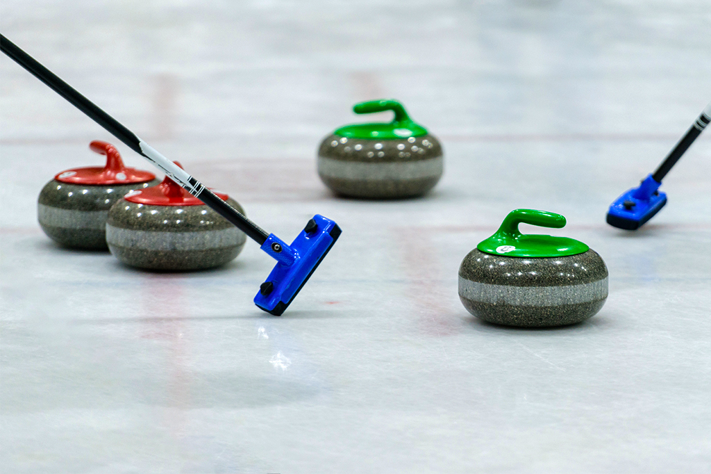 Imagem de pedras de curling na pista de gelo.