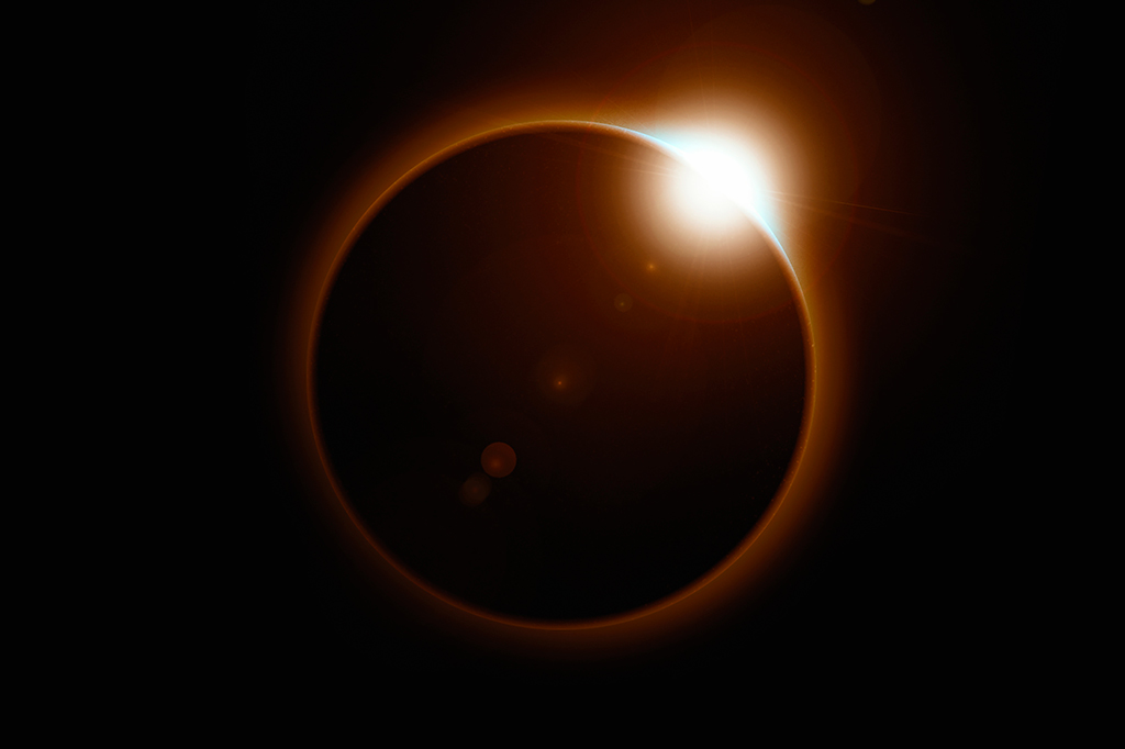 Fotografia de um eclipse solar, onde a lua se alinha perfeitamente para obscurecer o sol, projetando um brilho etéreo.
