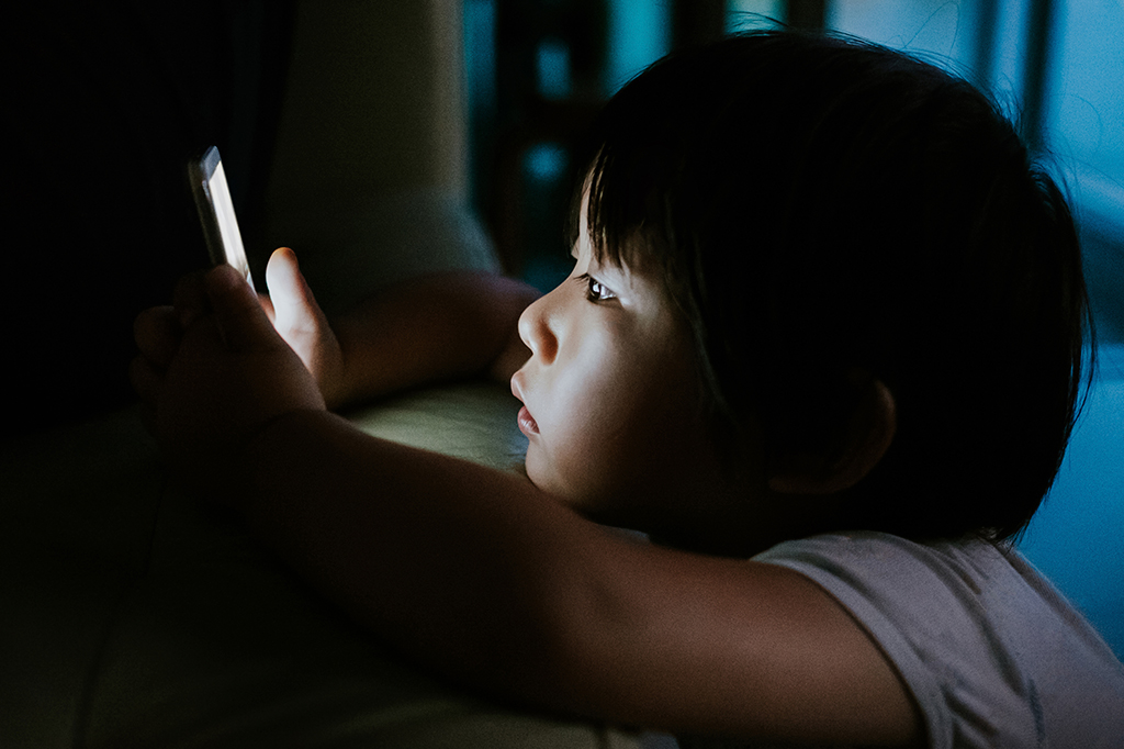 Fotografia de uma criança vidrada no celular.
