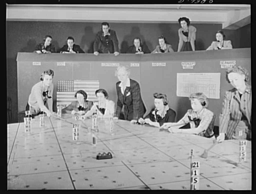 Imagem de mulheres durante a Segunda Guerra Mundial posicionando torres de cubos em um mapa.
