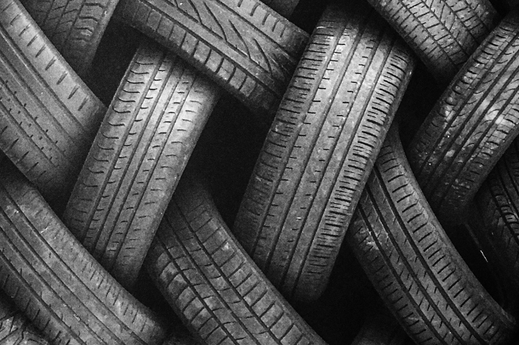 Imagem de diversos pneus usados amontoados em zigue-zague.
