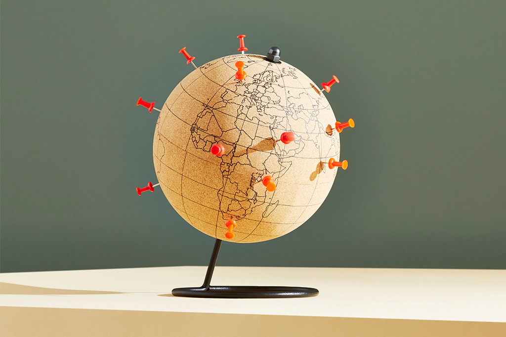 Imagem de um globo, em fundo cinza, com pins laranjas marcando alguns países.