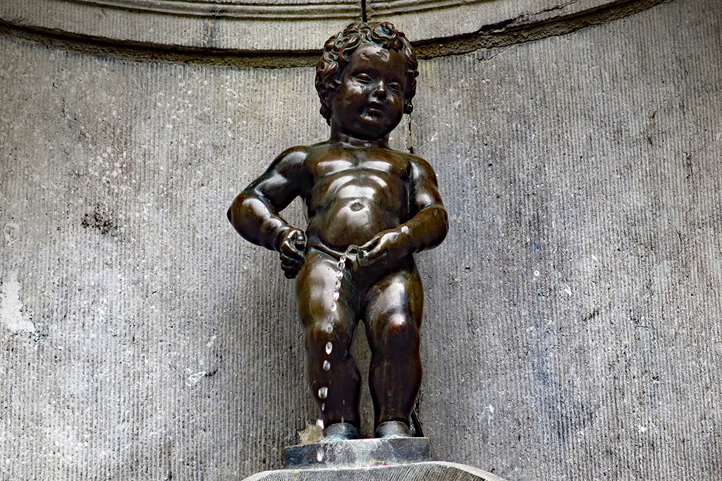 Fotografia de uma pequena fonte de bronze que representa um menino urinando.