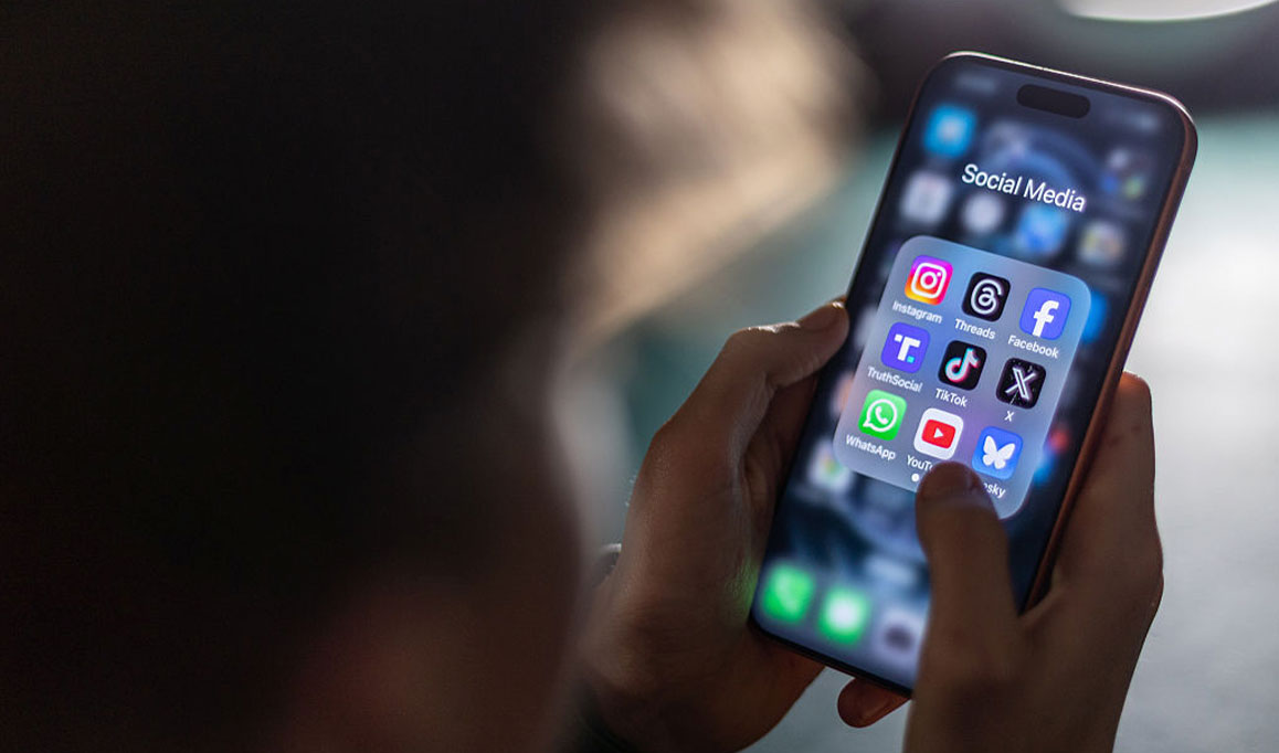 Foto aproximada das mãos de uma criança mexendo no celular com vários aplicativos de redes sociais abertas.