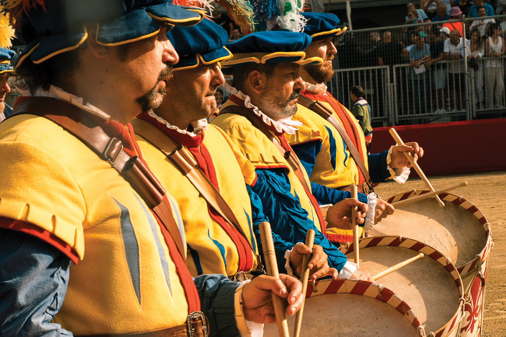 Fotografia de uma cena durante o torneio Calcio Storico Fiorentino de 2025: um grupo de homens vestidos com roupas renascentistas tocando tambor.