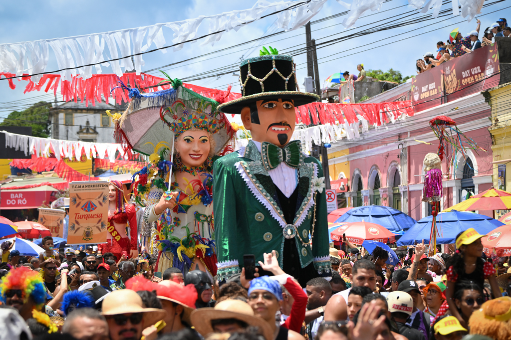 Imagem de uma multidão acompanhando um boneco gigante no carnaval de Olinda.