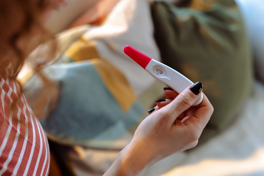 Fotografia de uma mulher segurando um teste de gravidez.