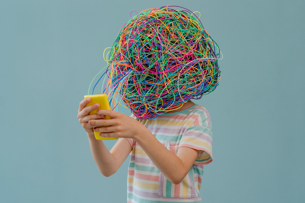 Imagem, em fundo verde, de uma criança com um emaranhado de fios na cabeça usando um smartphone amarelo.