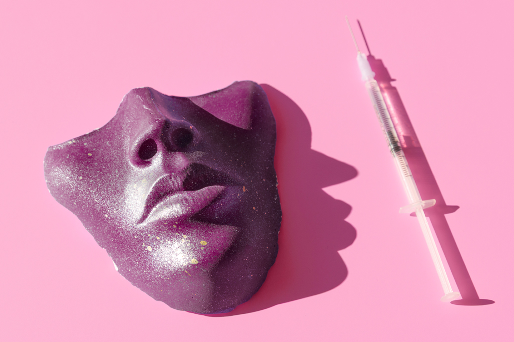 Imagem, em fundo rosa, de uma máscara ao lado de uma seringa com agulha.