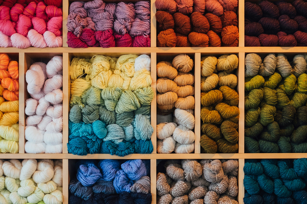 Uma de uma estante com novelos de lã de diversas cores.