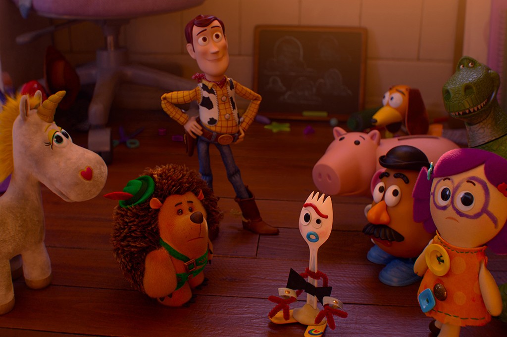 Os brinquedos de Toy Story, incluindo Woody, Forky, Porquinho, Sr. Cabeça de Batata, Sra. Cabeça de Batata, Rex, um unicórnio e um ouriço, estão reunidos em um quarto com piso de madeira, olhando para a frente com expressões variadas