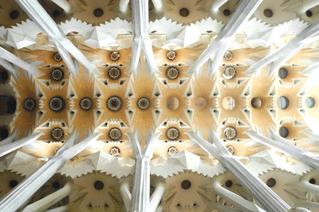 Teto de uma igreja com colunas brancas que se ramificam, sustentando pain&eacute;is geom&eacute;tricos em tons de bege e branco, com detalhes circulares e estrelados