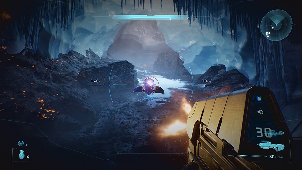 Vis&atilde;o em primeira pessoa de um jogo de tiro, com uma arma futurista em primeiro plano e um inimigo flutuante roxo ao centro da mira. O cen&aacute;rio &eacute; uma caverna gelada com forma&ccedil;&otilde;es rochosas escuras e estalactites de gelo, iluminada por uma luz azulada. Elementos da interface do jogo, como radar e contagem de muni&ccedil;&atilde;o, s&atilde;o vis&iacute;veis
