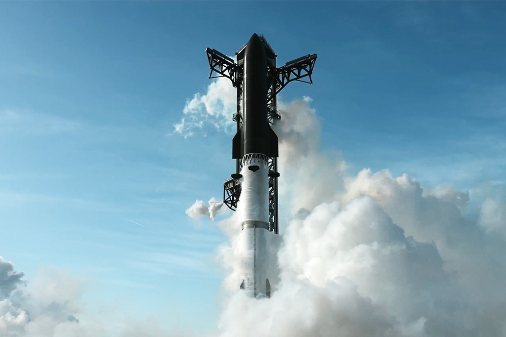 Foguete espacial preto e branco, com estrutura de lançamento preta, subindo em meio a uma grande nuvem de fumaça branca contra o céu azul