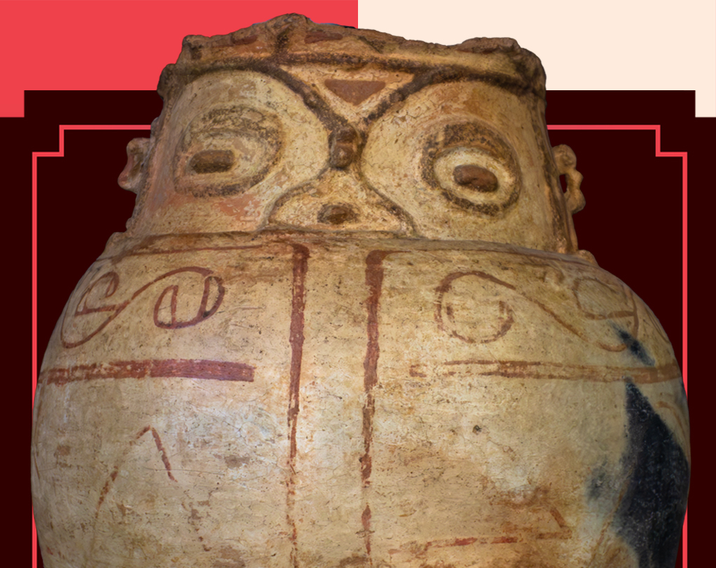 Vaso cerâmico pré-colombiano em tons terrosos, com rosto estilizado na parte superior, olhos ovais e boca triangular. Desenhos geométricos e espirais em vermelho e marrom decoram o corpo do vaso, sobre fundo vermelho e bege