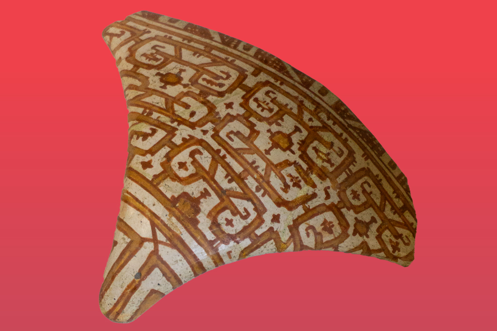 Tanga de cerâmica pré-colombiana em tons de bege e marrom, com padrões geométricos complexos e linhas curvas interligadas, sobre um fundo vermelho liso